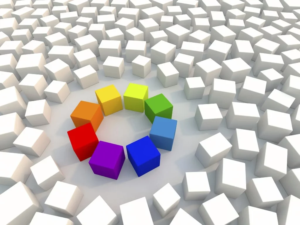 Auf den Bild sieht man Quader. Ein Teil davon ist farbig und im Kreis angeordnet. Es sieht so als würden die anderen weißen ungeordneten Quader dazu kommen wollen. Das Bild illustriert ein Projekt bei dem viele Beteiligten zu einem System verschmolzen wurden.
