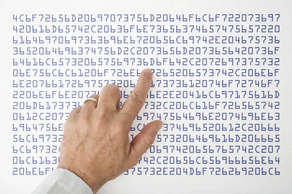 Auf den Bild sind zahlen und Buchstaben zu sehen und einen Mensch mit den Zeigefinger auf ein drauf zeigt. Wir bei aitimatic erkennen die Probleme auch in komplexen systemen.